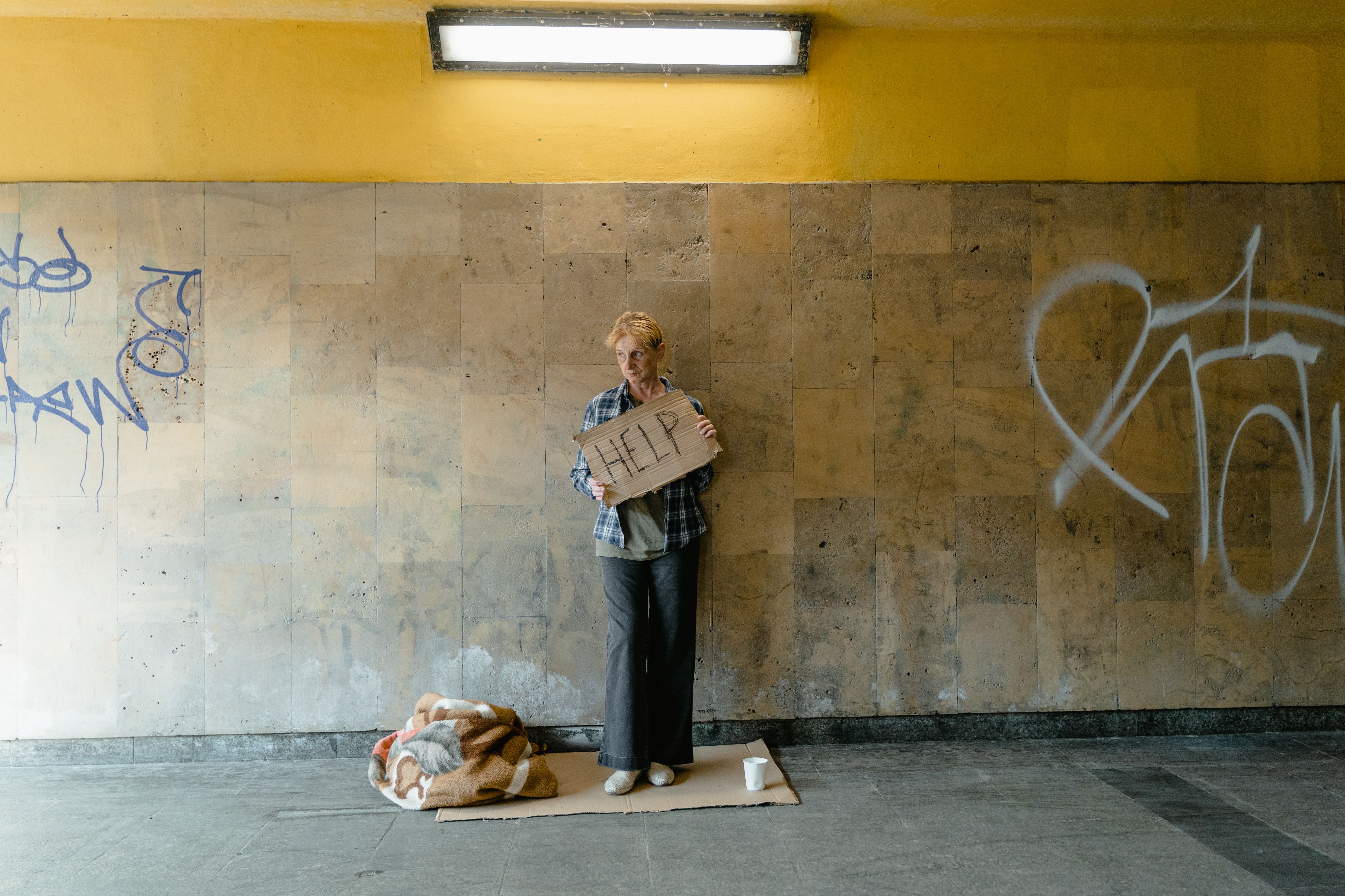 Senior woman holding a HELP sign in an urban area, symbolizing vulnerable people needing aid
