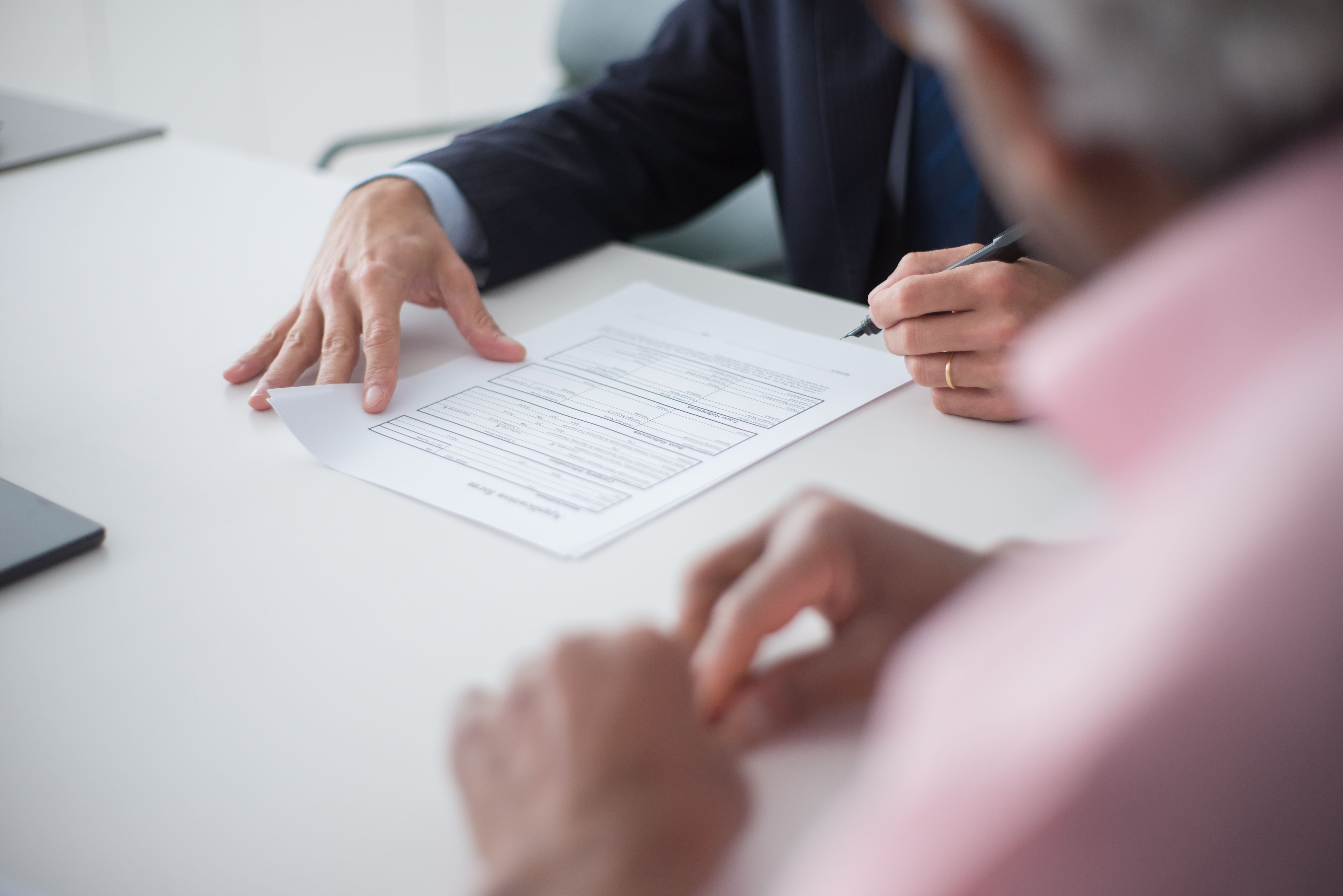 Two professionals review and sign documents during a private business meeting, representing confidentiality agreements.