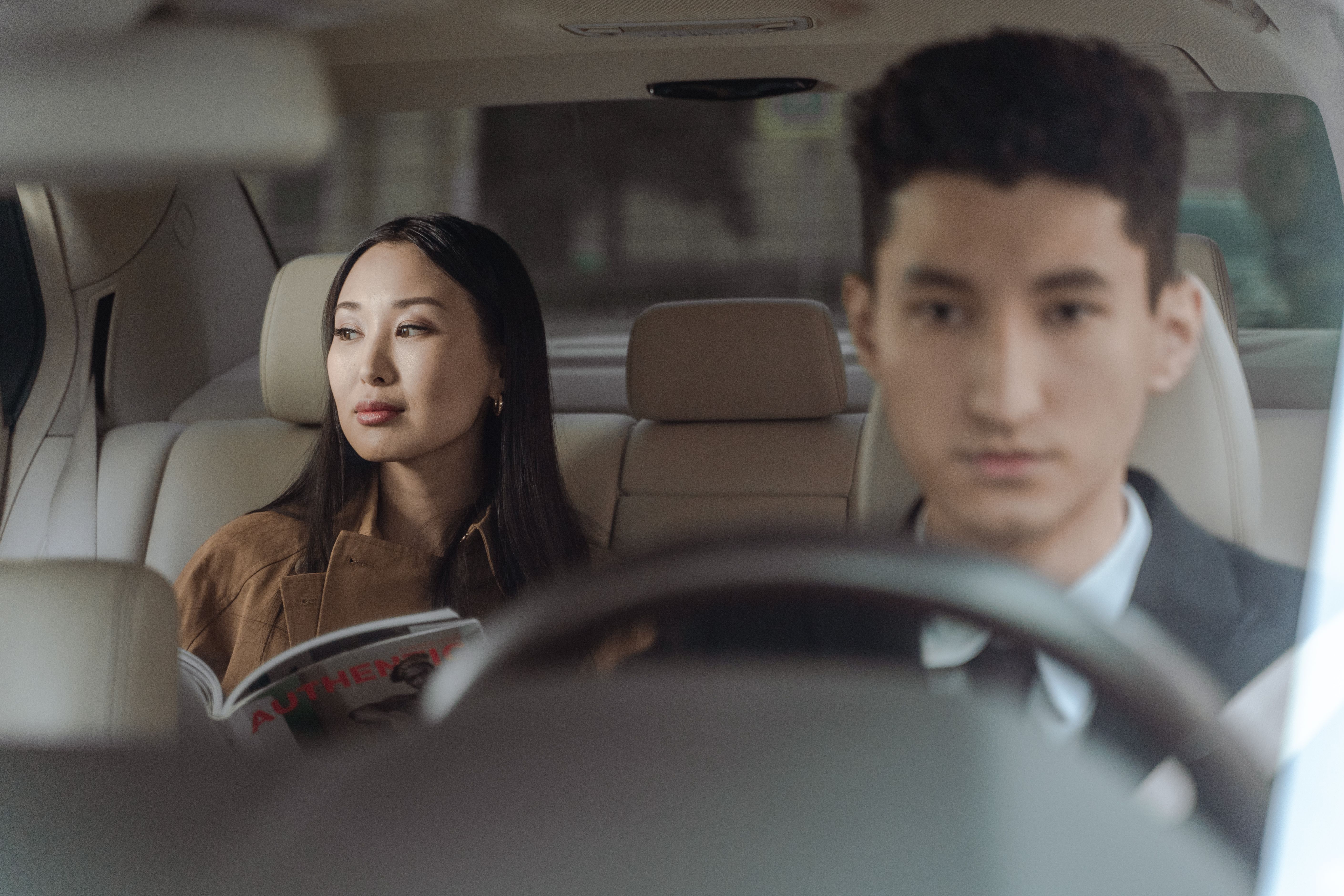 A businesswoman and chauffeur inside a luxury car, illustrating discreet transportation for high-profile clients.